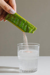 Hand pouring Nottevit Skinny Sleep Collagen powder into a glass of water for weight loss and improved sleep.